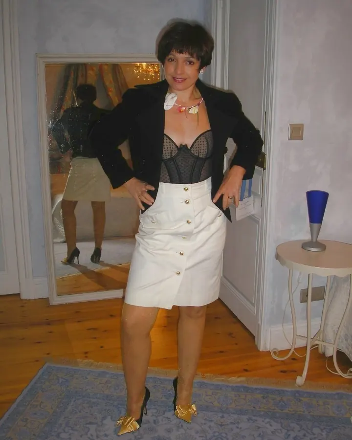 Femme en robe noire, debout près d'une porte, main sur la hanche