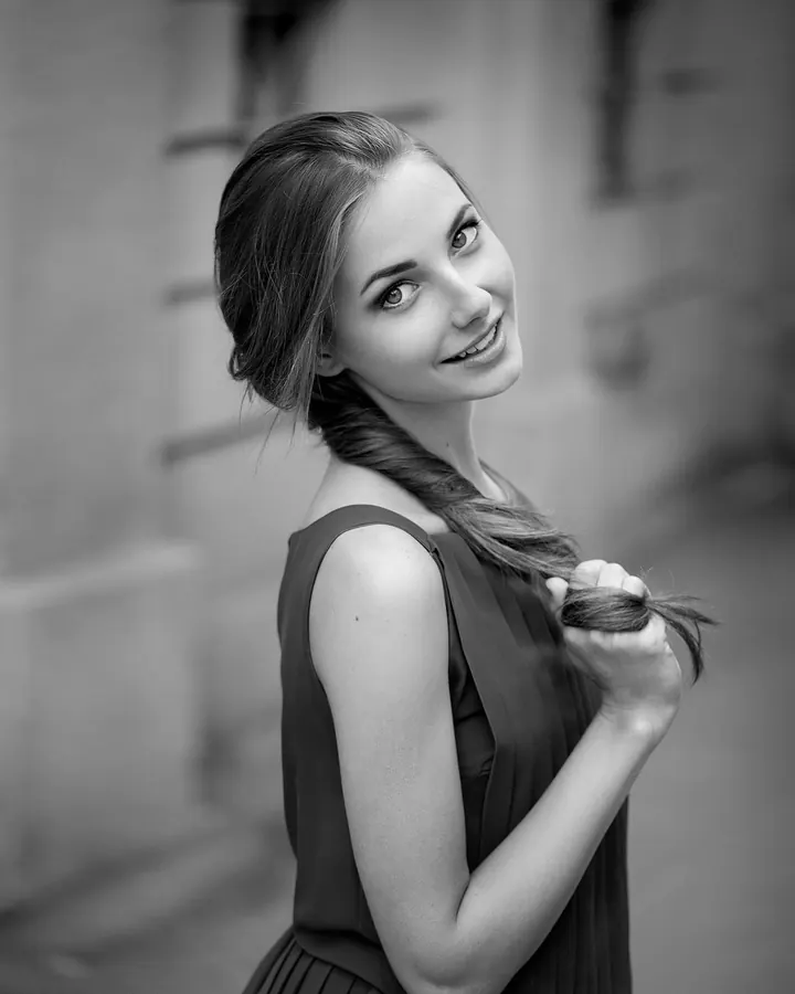 Femme blonde en robe noire, souriant à la caméra dans un portrait en noir et blanc