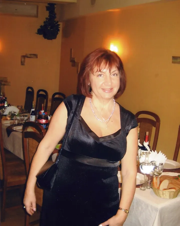 Femme mûre en robe magenta, collier 'SLUT', sourire, ambiance intime