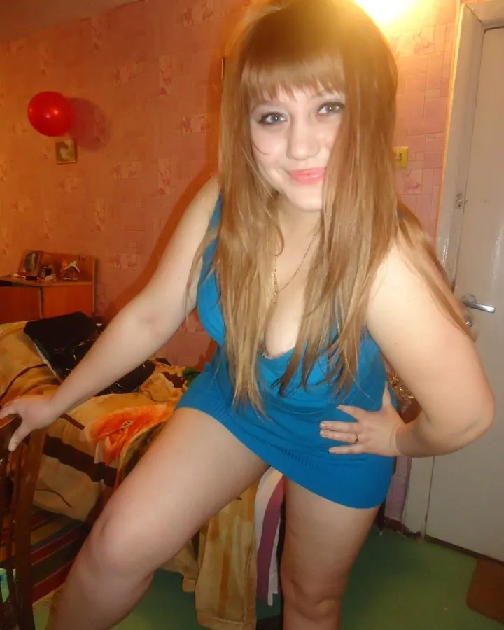 Femme blonde, en robe noire, posant dans un couloir