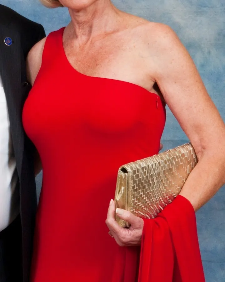 Femme blonde en robe rouge, posant devant un fond bleu