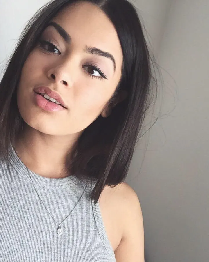 Portrait d'une jeune femme aux cheveux foncés, regardant directement l'objectif.