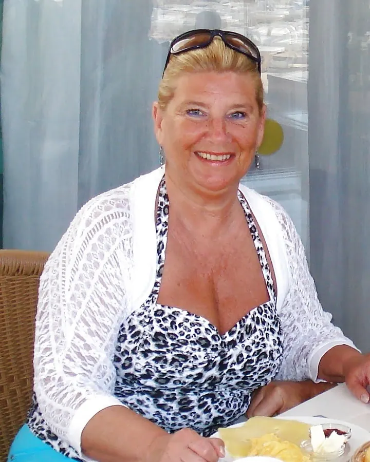 Femme blonde en tenue décontractée, assise à table avec une assiette de nourriture