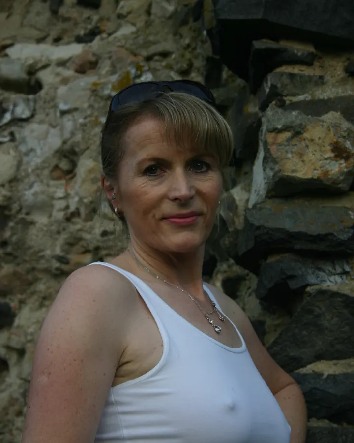 Femme aux cheveux bruns, regard fixe, en haut clair, fond neutre
