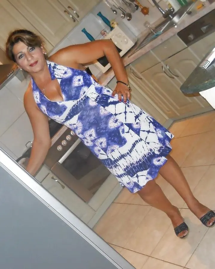 Femme mûre en robe bleue et blanche dans une cuisine
