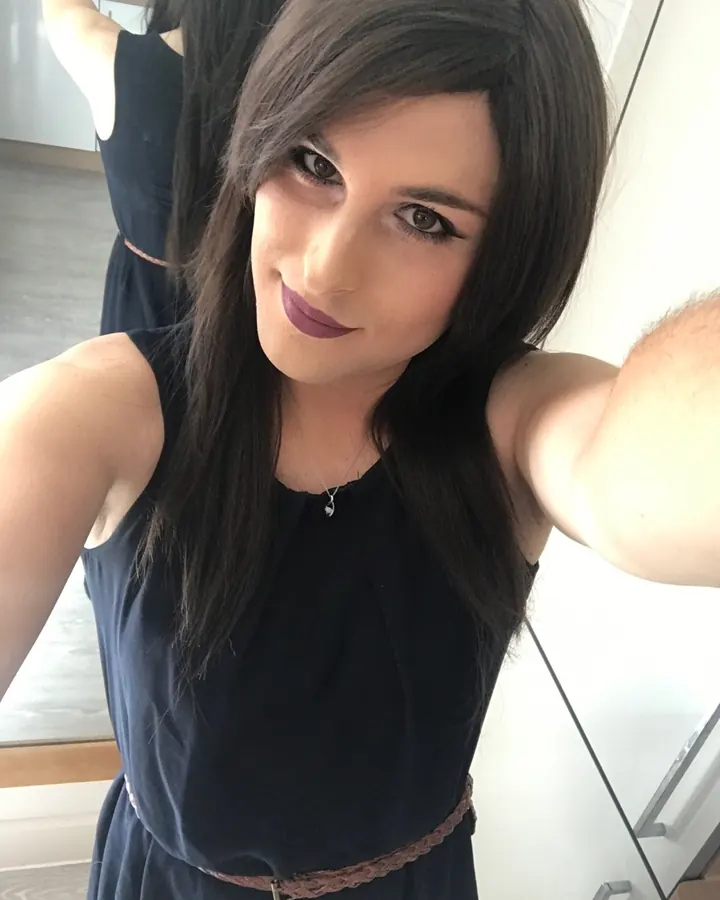 Femme brune en robe noire, collier fin, selfie